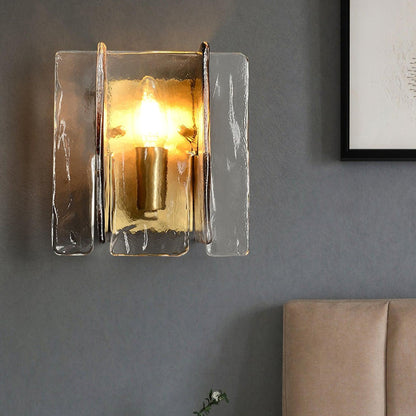 A wall-mounted light fixture with a unique glass design, casting a warm amber glow in a modern bedroom.