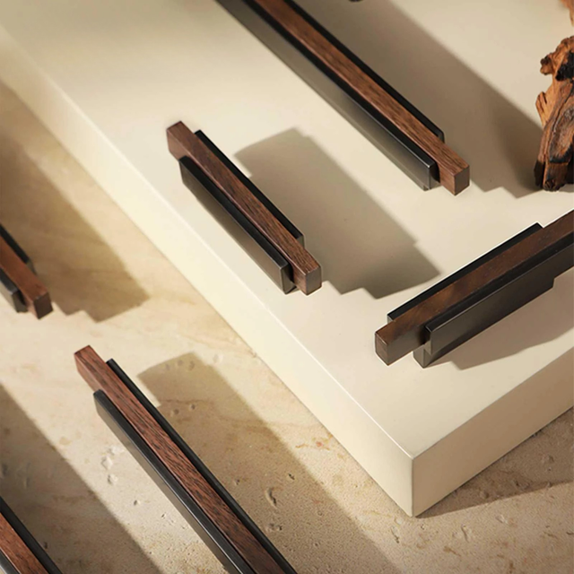 Modern bronze and wood cabinet handles displayed on a light beige background with warm lighting