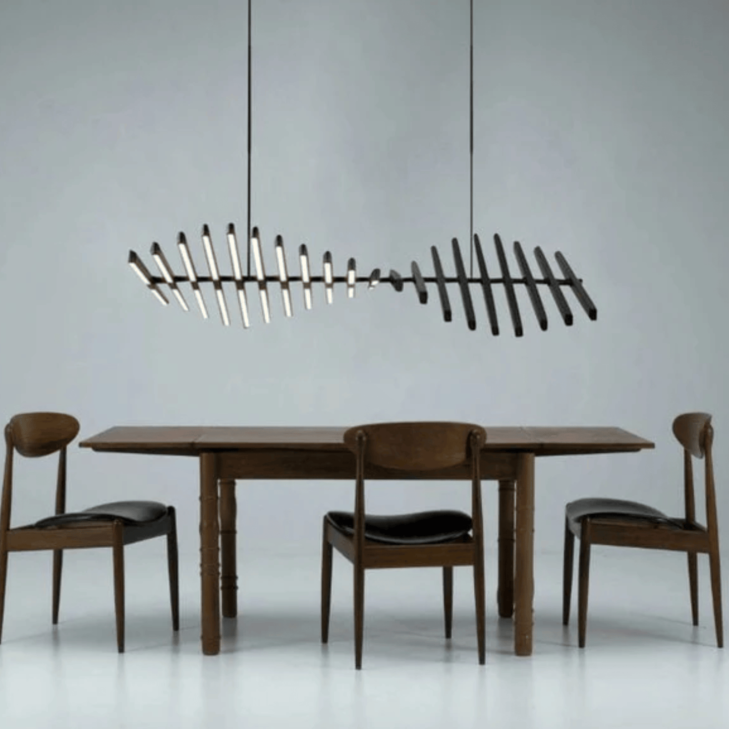Dining table with chairs and a modern chandelier against a gray background