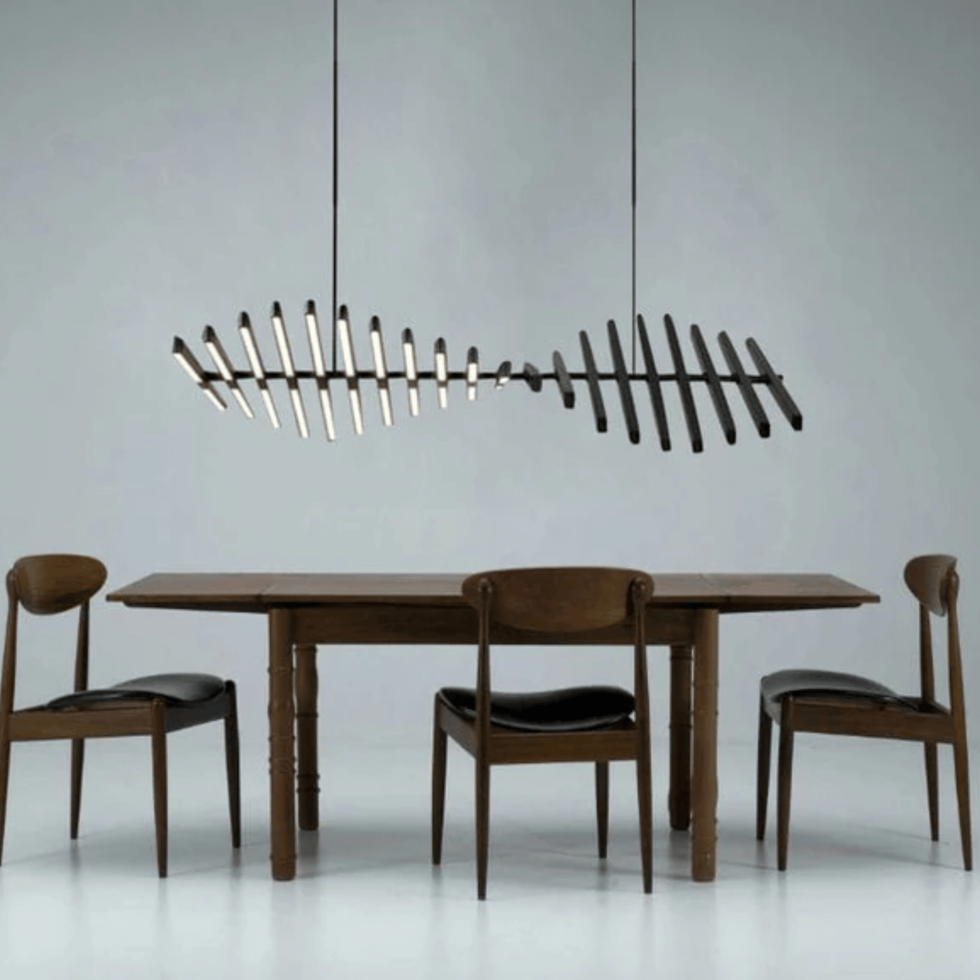 Dining table with chairs and a modern chandelier against a gray background