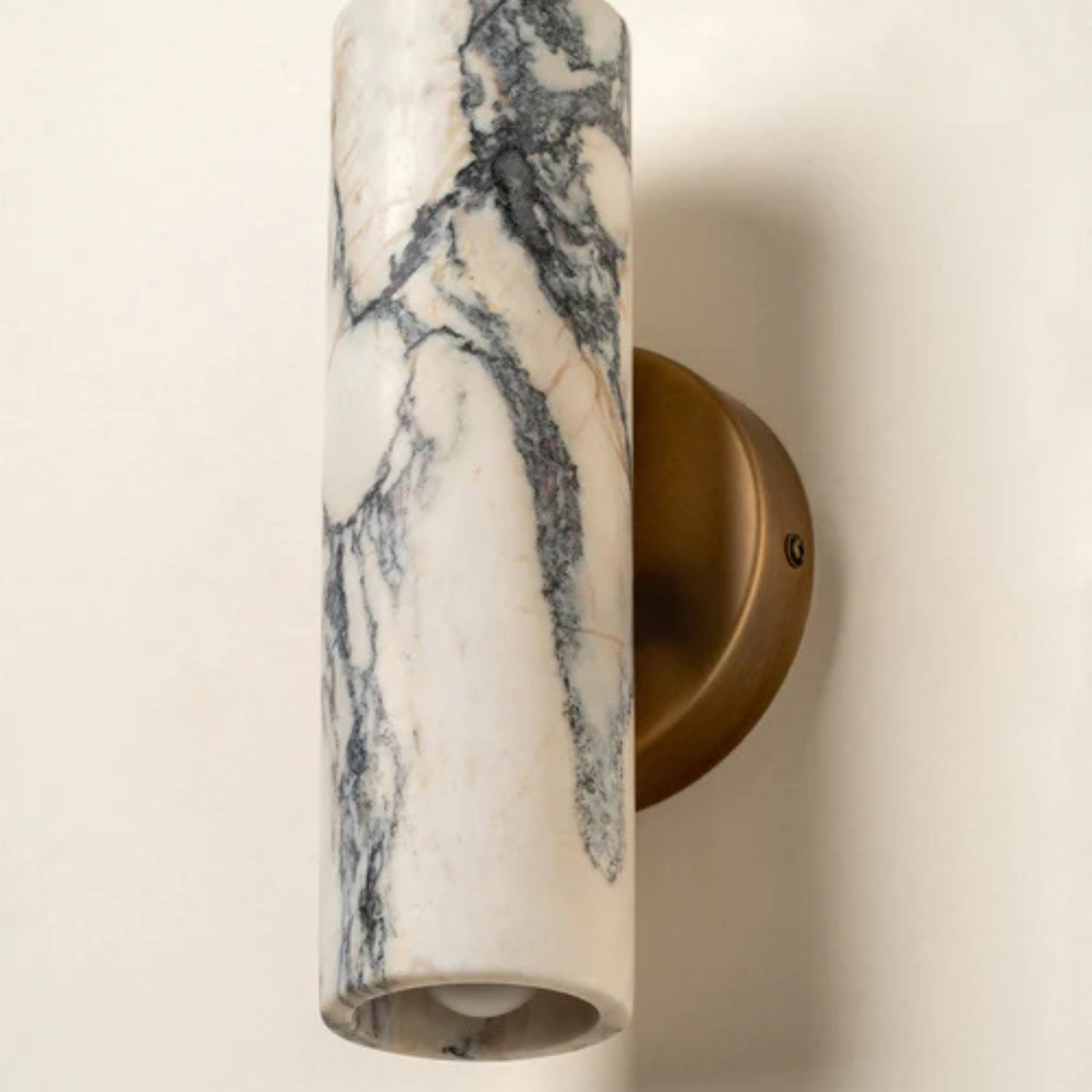 Close-up view of a vertical marble wall sconce with a brass mount and warm ambient light.