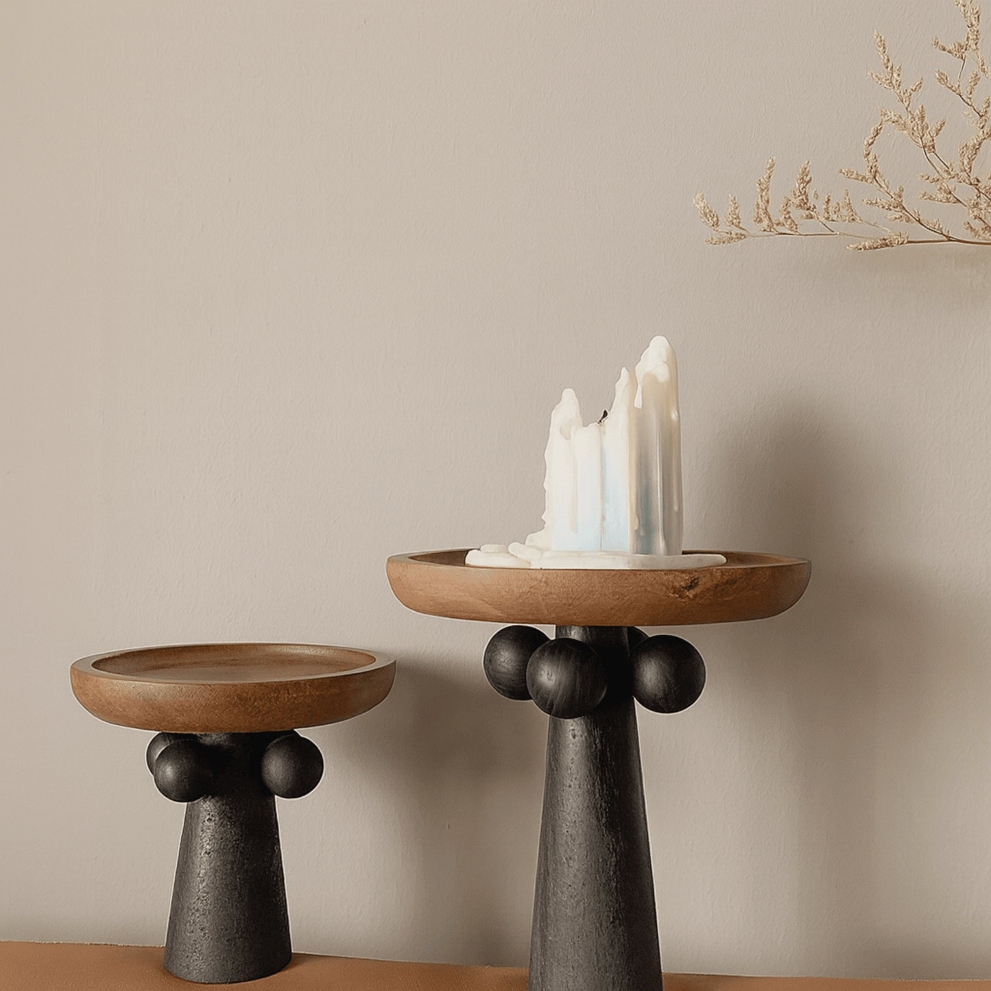 Two wooden candle holders with black bases on a neutral background