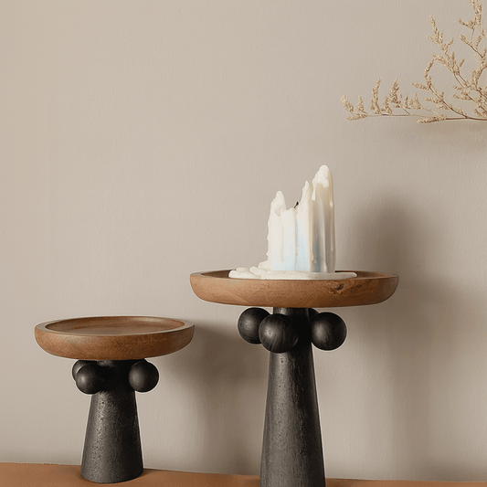 Two wooden candle holders with black bases on a neutral background
