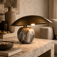 Decorative table lamp with marble base on a wooden surface in a cozy room setting.