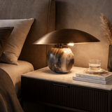 Decorative lamp on a nightstand with books and a glass of water in a cozy room.