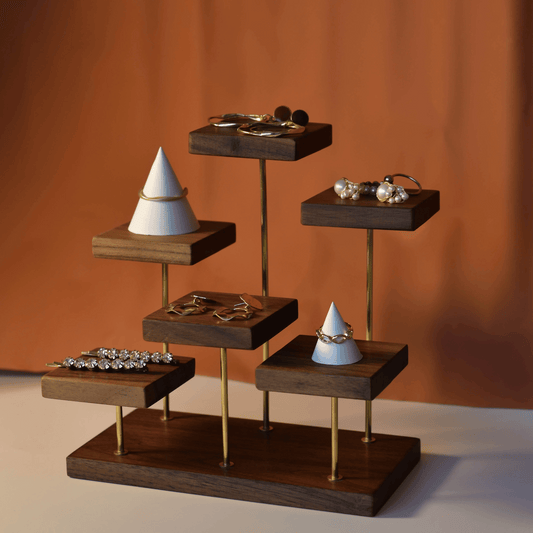 Wooden jewelry display with cones and rings on an orange background