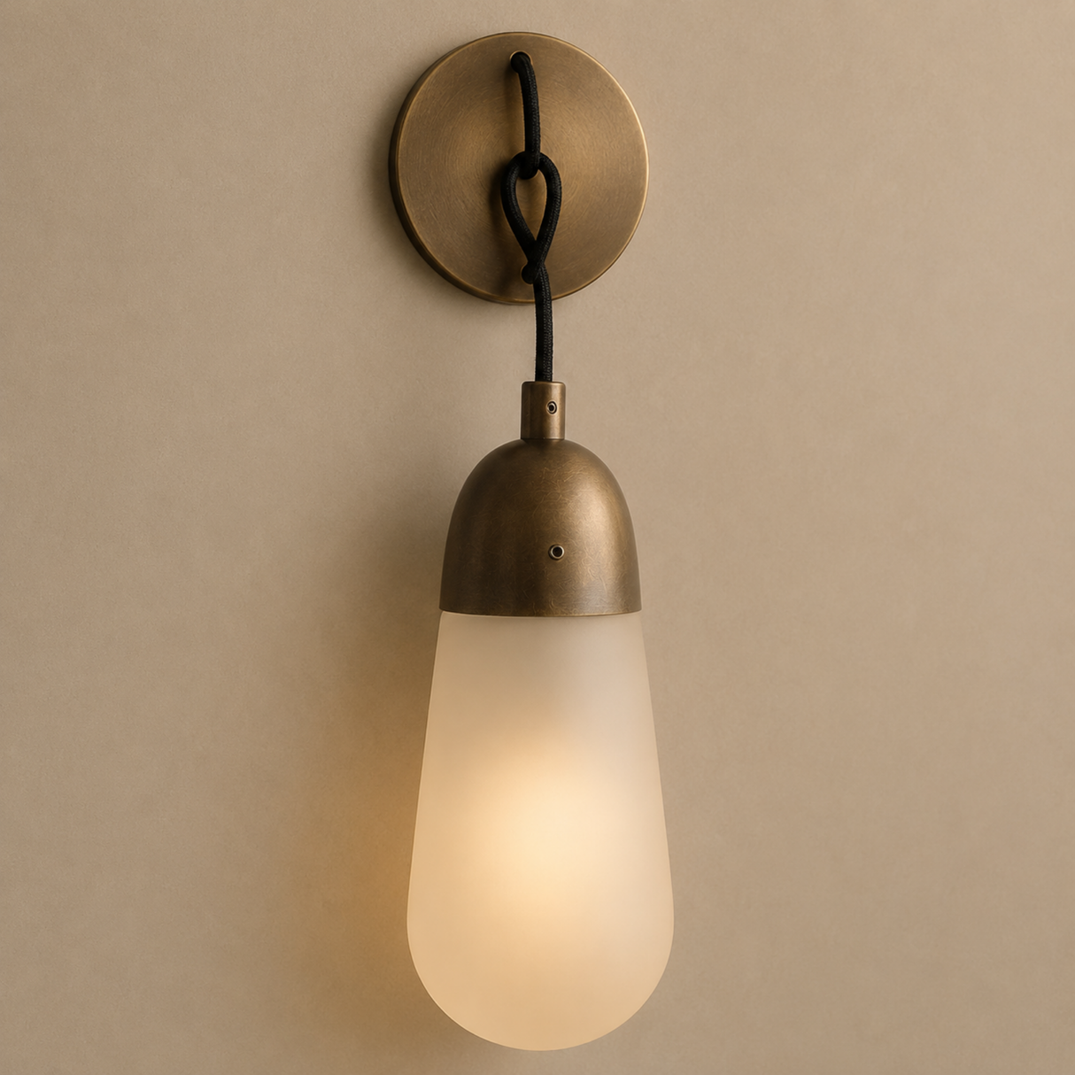 Brass wall sconce with a glass shade on a beige wall