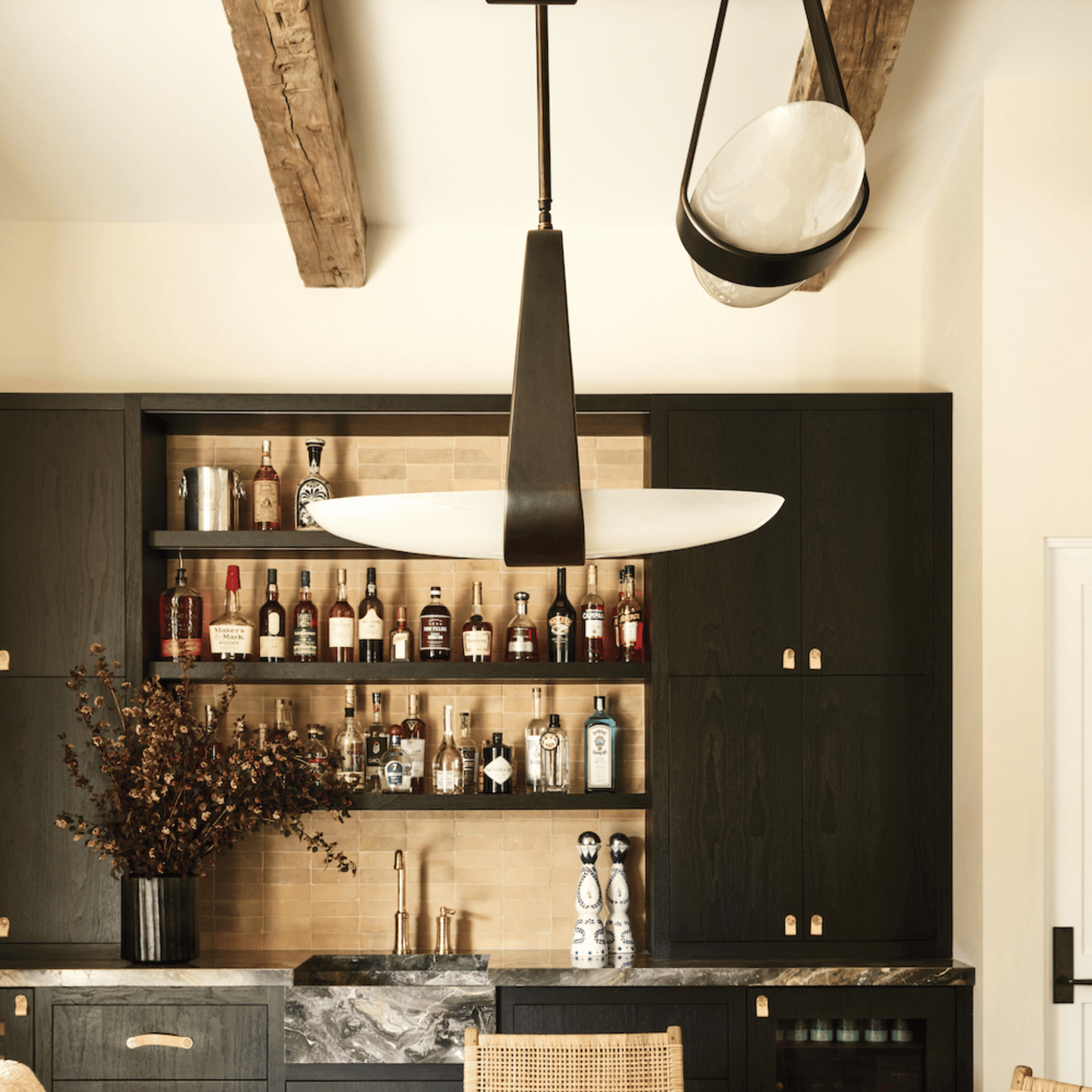 Modern kitchen with dark cabinets, pendant lights, and a bar setup.