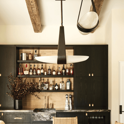 Modern kitchen with dark cabinets, pendant lights, and a bar setup.