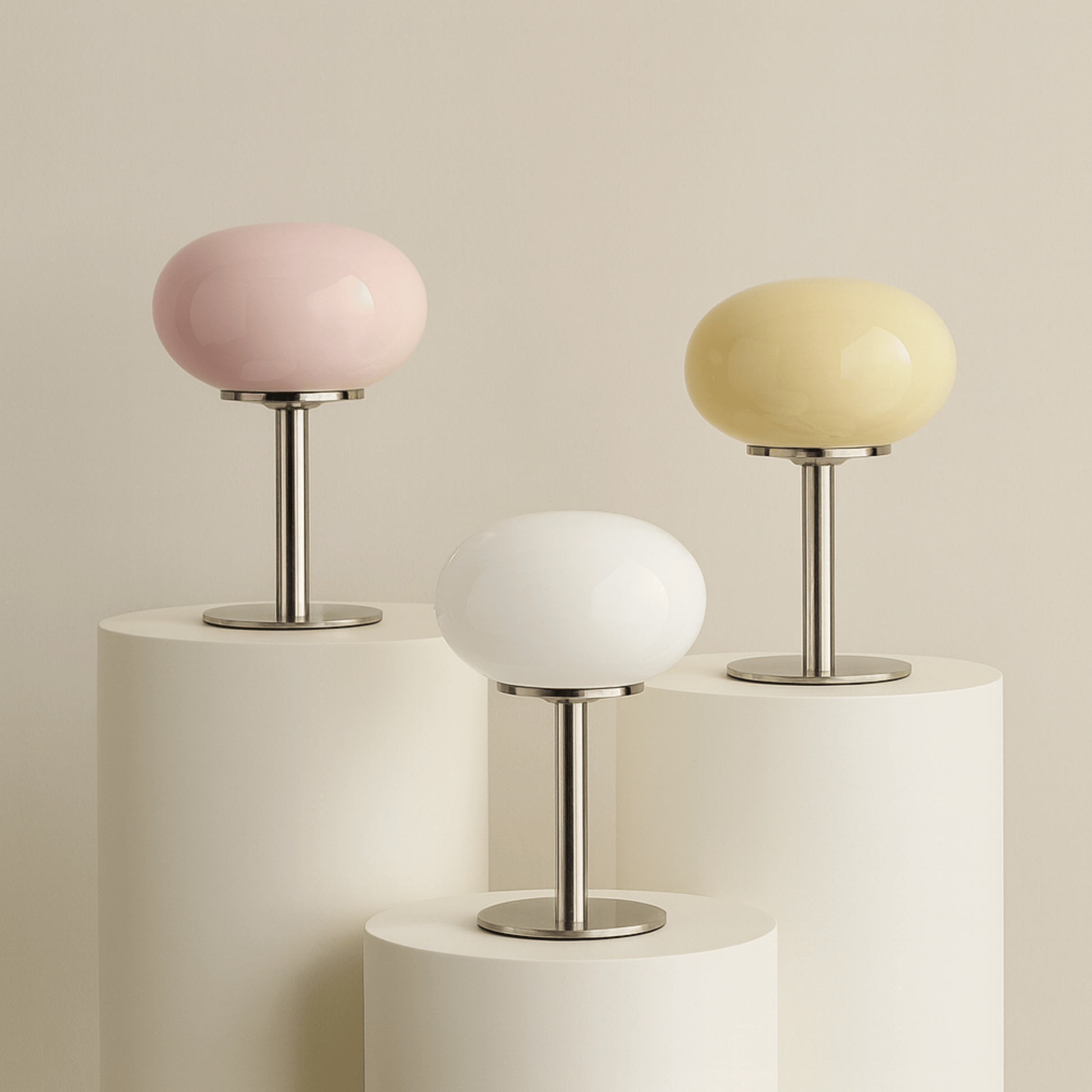 Three small table lamps with pastel-colored shades on cylindrical bases against a beige background.