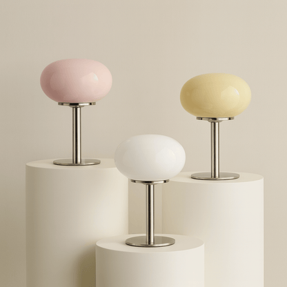 Three small table lamps with pastel-colored shades on cylindrical bases against a beige background.