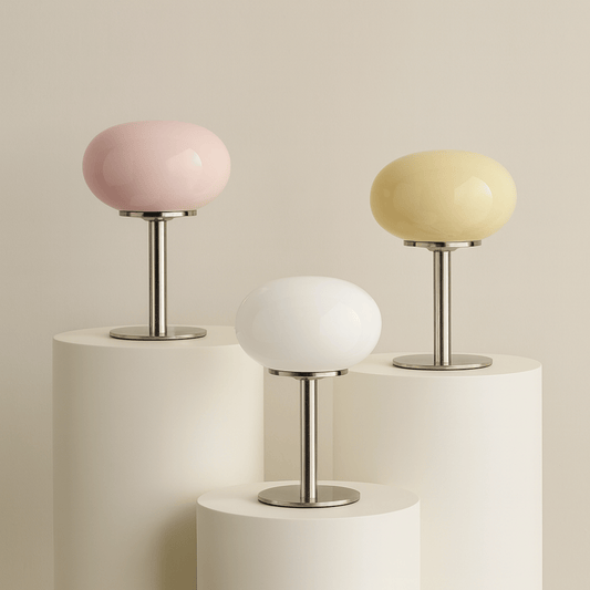 Three small table lamps with pastel-colored shades on cylindrical bases against a beige background.