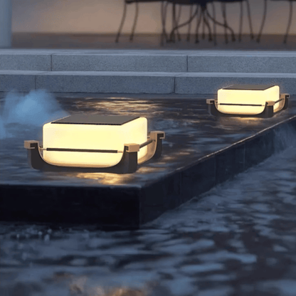 Two modern outdoor lights on a stone ledge near water