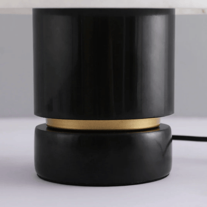 Black cylindrical lamp with gold accent on a white surface