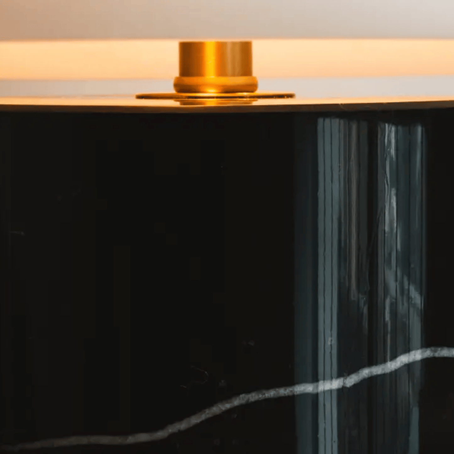 Black cylindrical object with a gold top on a light background