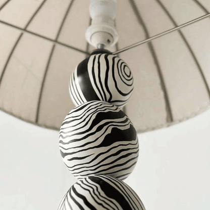 Decorative lamp with black and white striped design on a neutral background
