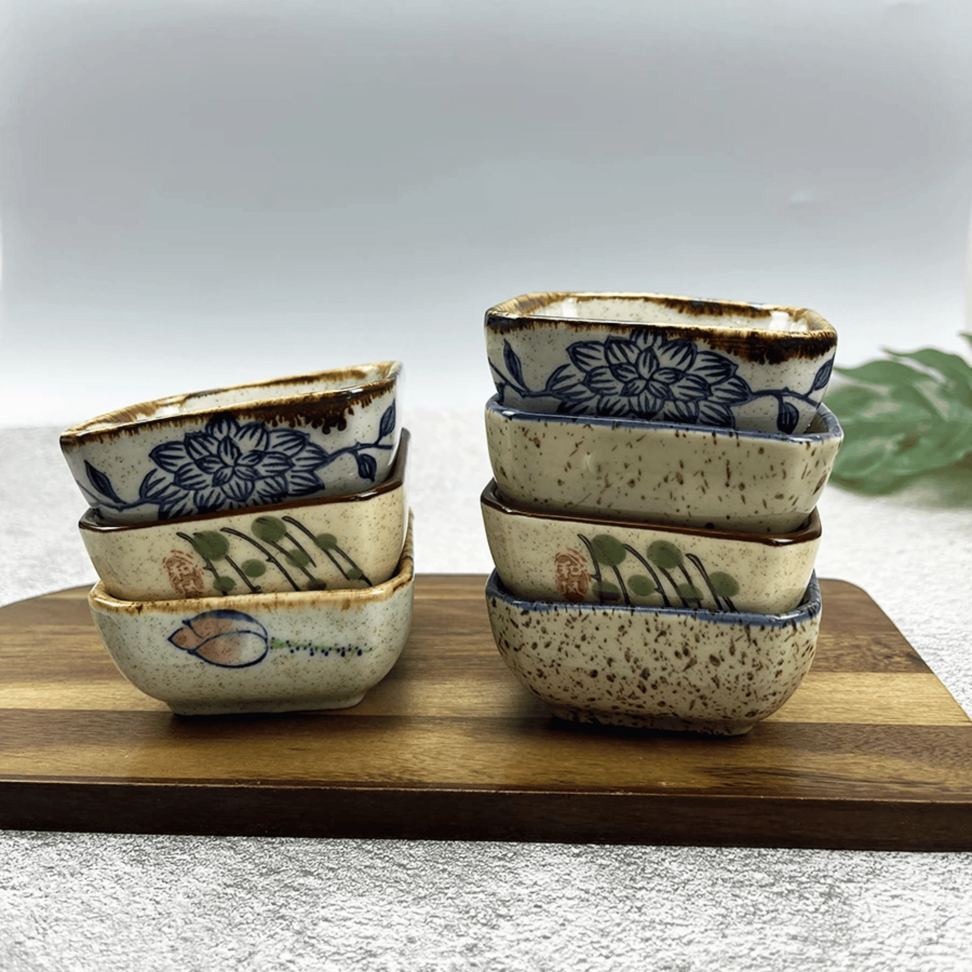 Set of ceramic bowls with floral and leaf patterns on a wooden board.