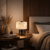Modern bedroom with a bedside table, lamp, and books.