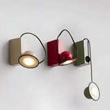 Modern wall-mounted light fixture with three different colored lights on a white background