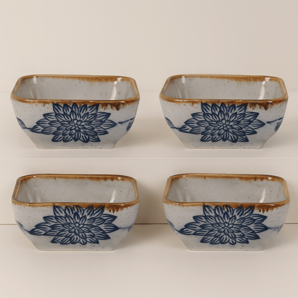 Four square ceramic bowls with blue floral patterns and brown edges on a white background