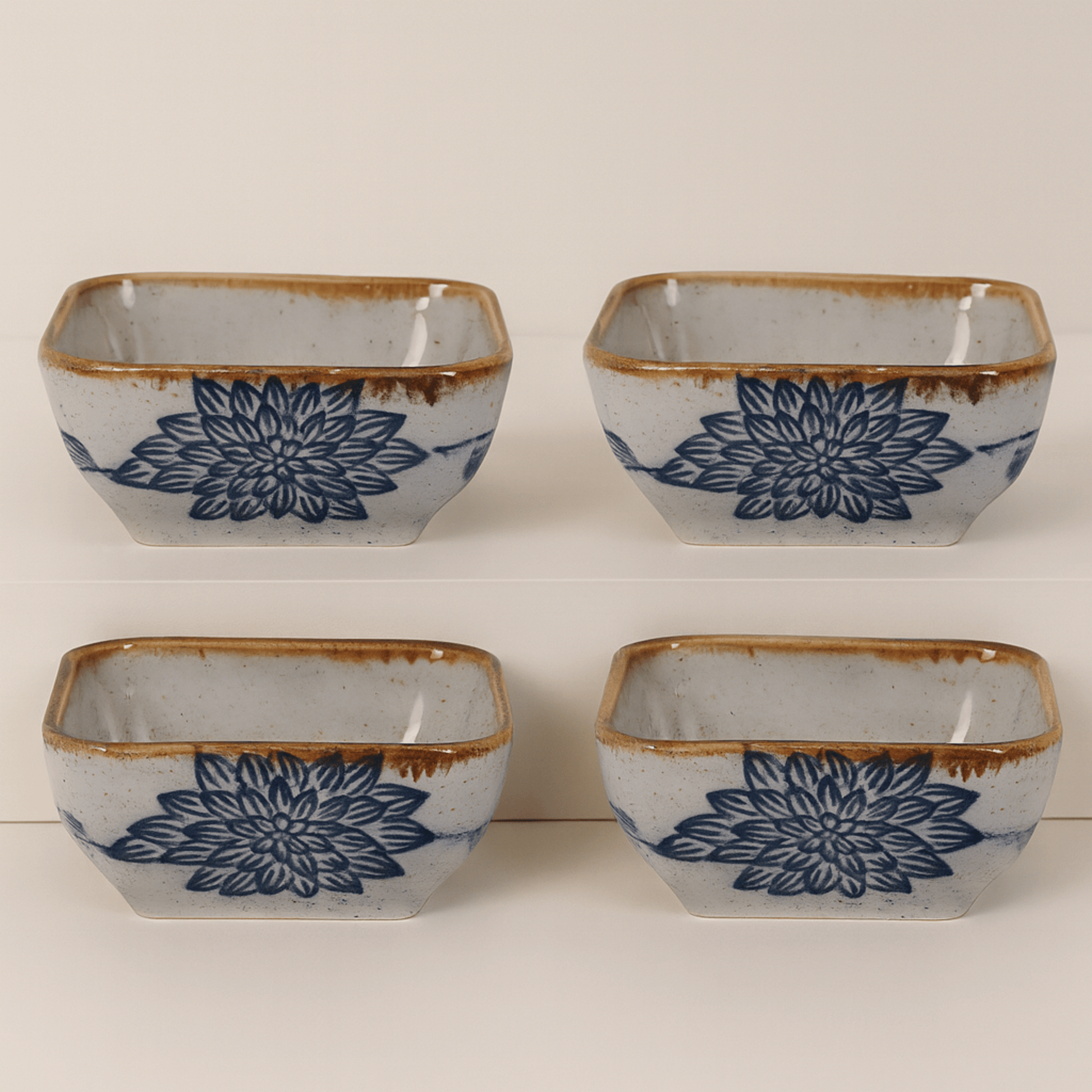 Four square ceramic bowls with blue floral patterns and brown edges on a white background