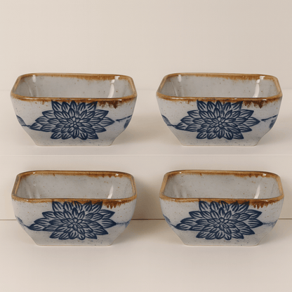 Four square ceramic bowls with blue floral patterns and brown edges on a white background