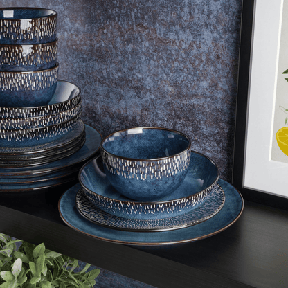 Set of blue ceramic dinnerware with textured design on a dark surface.