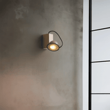 Wall-mounted light fixture on a textured wall with a window in the background