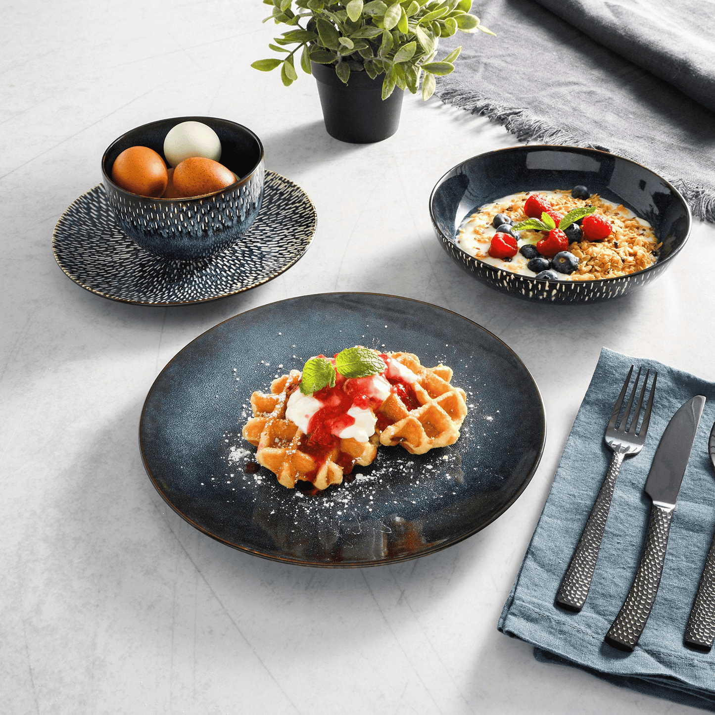 Dessert plates with waffles and fruit on a light gray surface.