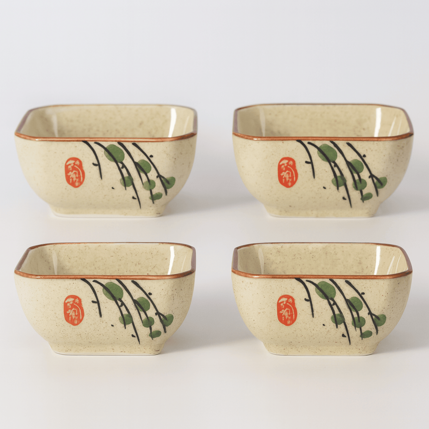 Four square ceramic bowls with decorative elements on a white background