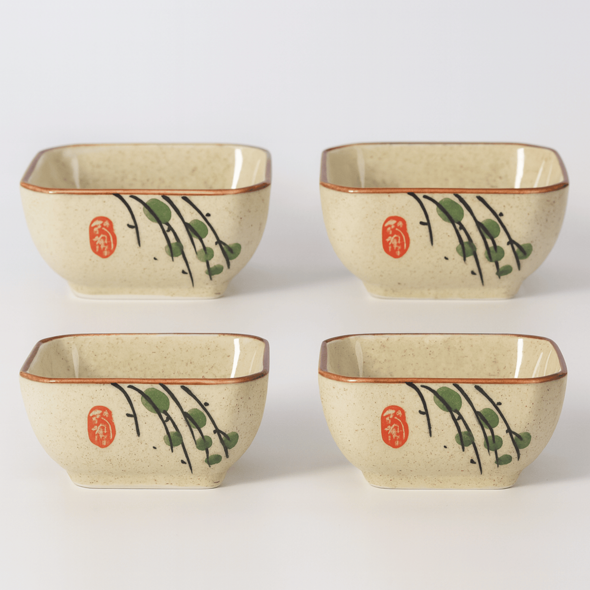 Four square ceramic bowls with decorative elements on a white background
