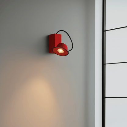 Red wall light fixture on a gray wall with a black metal ladder in the background
