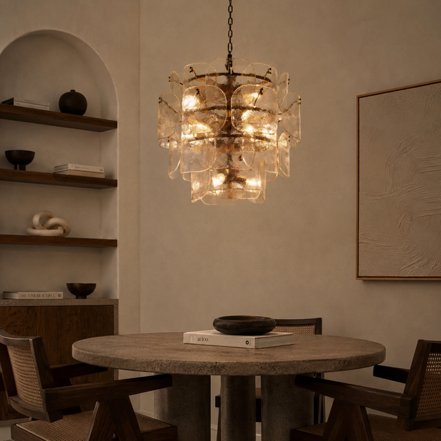 Modern chandelier hanging above a dining table in a dimly lit room.