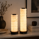 Two cylindrical table lamps with stacked ring design on a surface with decorative items.
