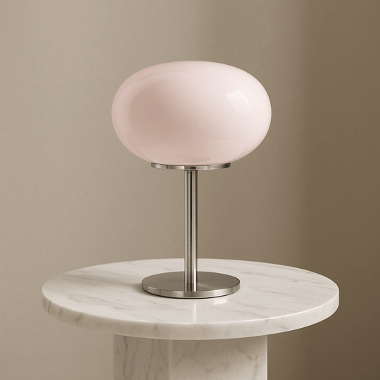 Table lamp with a pink glass shade on a marble base against a beige wall