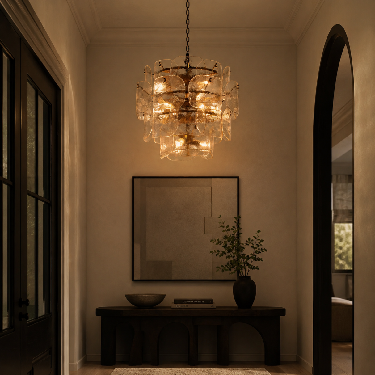 Luxurious interior with a chandelier, mirror, and plant in a dimly lit room.