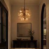 Luxurious interior with a chandelier, mirror, and plant in a dimly lit room.