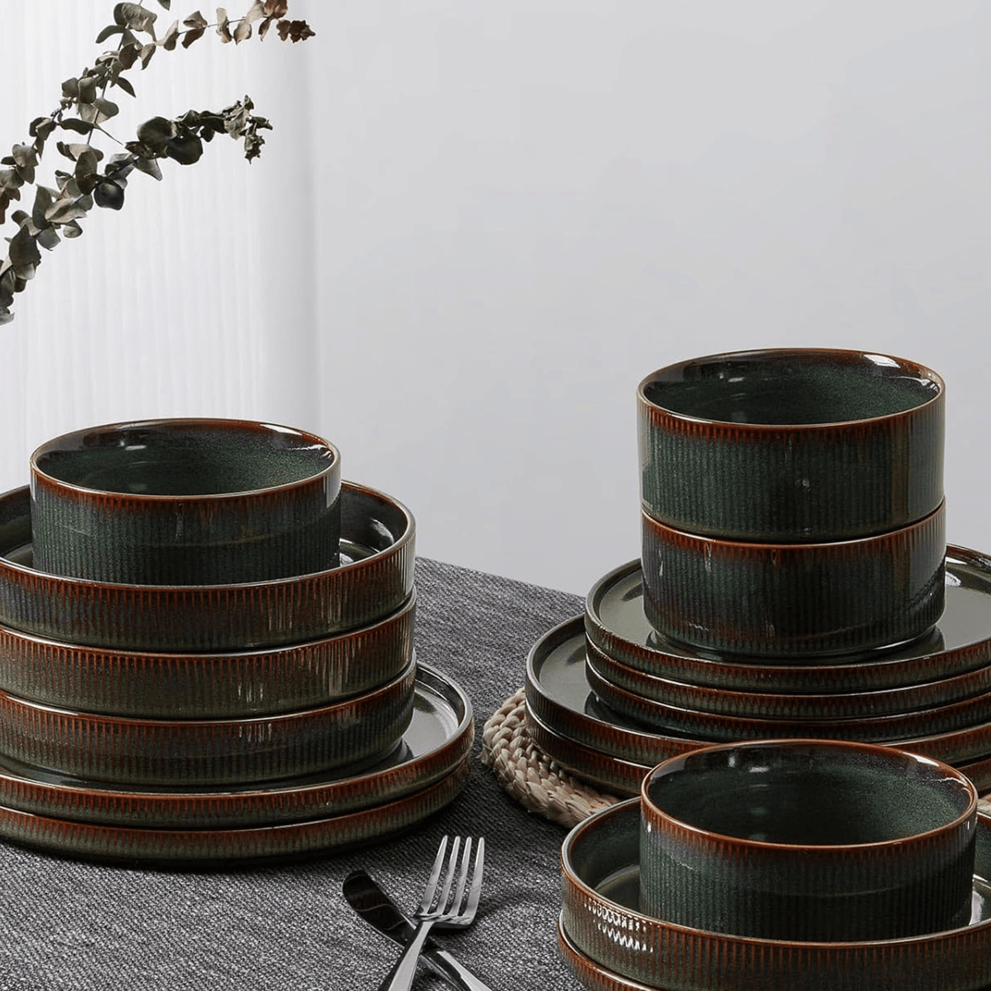 Set of green ceramic dinnerware with brown rim on a gray surface.