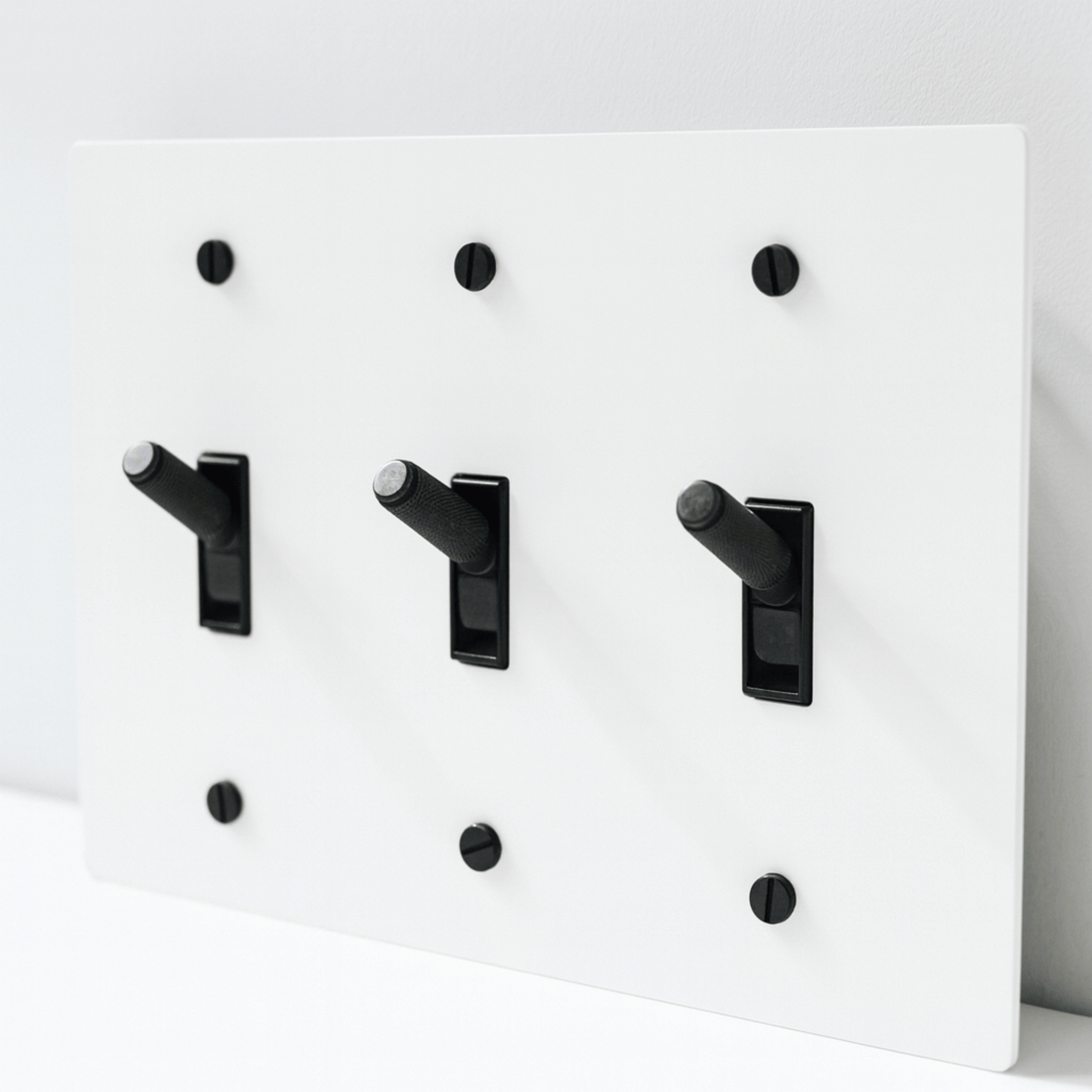 White wall plate with black toggle switches on a white background