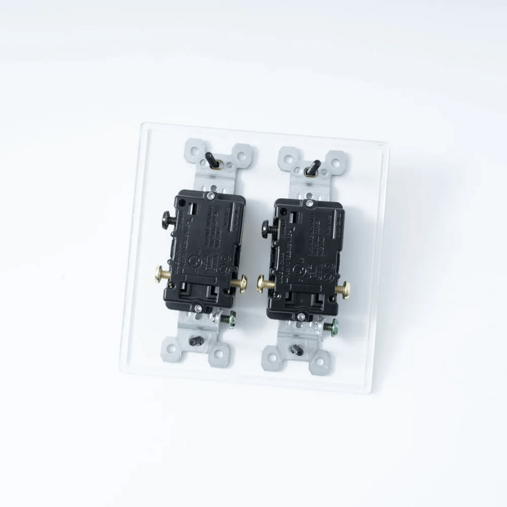 Two black electrical switches on a clear plastic base against a white background