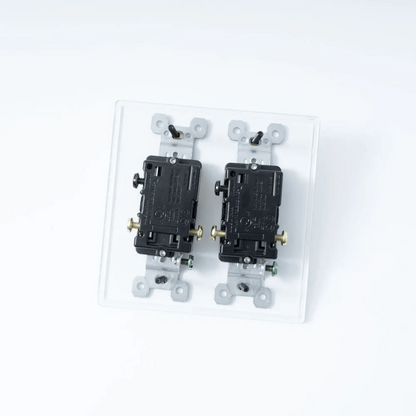 Two black electrical switches on a clear plastic base against a white background