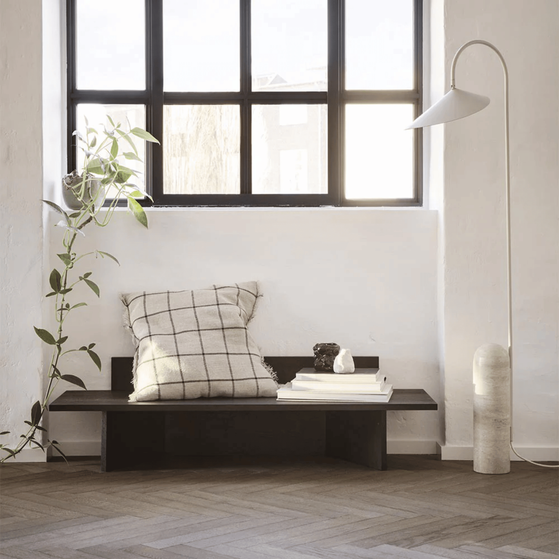 Modern interior with a bench, cushion, and decorative items near a large window.