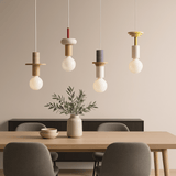 Dining room with pendant lights, table, chairs, and a vase with greenery.