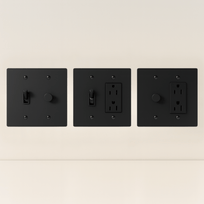 Three black wall switches and outlets on a beige background