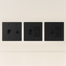 Three black wall switches and outlets on a beige background