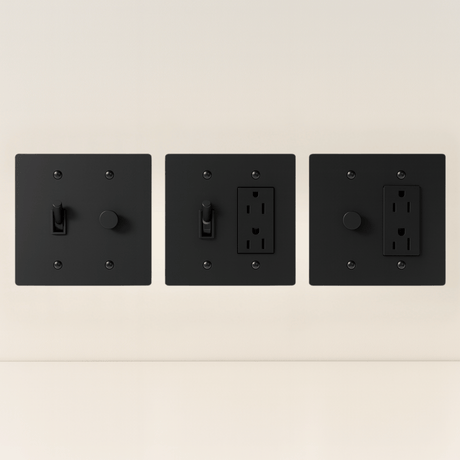 Three black wall switches and outlets on a beige background