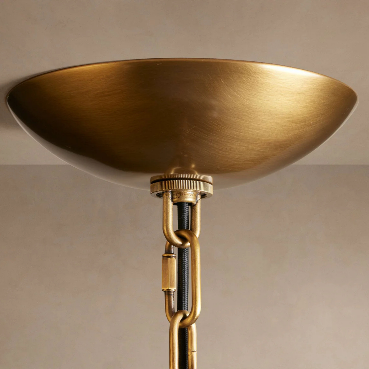 Close-up of a gold ceiling light fixture against a beige wall.