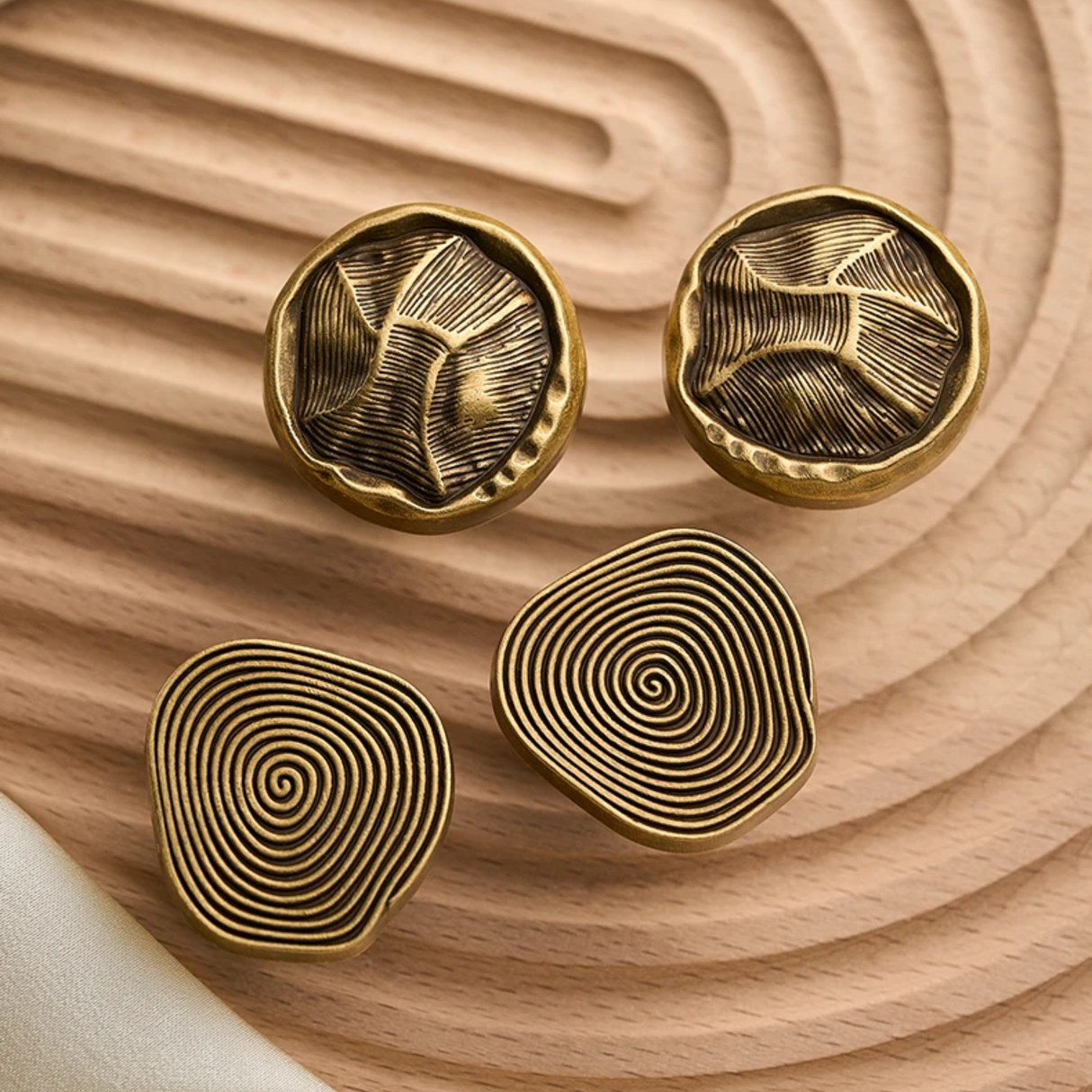 Four gold cufflinks with unique patterns on a wooden surface