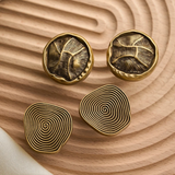 Four gold cufflinks with unique patterns on a wooden surface