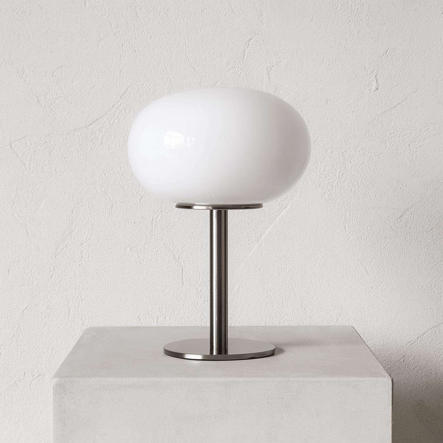 Table lamp with white shade and metal base on a light gray background